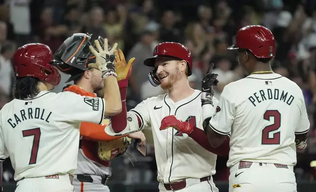 Arizona Diamondbacks' Pavin Smith, center, celebrates his three-run home run against the San Francisco Giants with Corbin Carroll (7) and Geraldo Perdomo (2) during the eighth inning of a baseball game Wednesday, Sept. 25, 2024, in Phoenix. (AP Photo/Ross D. Franklin)