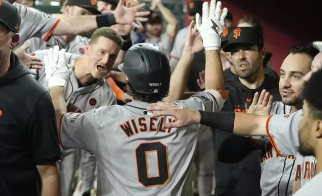 San Francisco Giants' Brett Wisely (0) celebrates in the dugout with teammates after hitting a three-run home run against the Arizona Diamondbacks during the third inning of a baseball game Tuesday, Sept. 24, 2024, in Phoenix. (AP Photo/Ross D. Franklin)