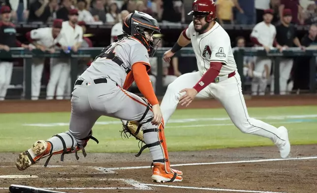 Arizona Diamondbacks' Eugenio Suárez, right, starts his slide into home plate to score a run ahead of a tag by San Francisco Giants catcher Patrick Bailey during the second inning of a baseball game Wednesday, Sept. 25, 2024, in Phoenix. (AP Photo/Ross D. Franklin)