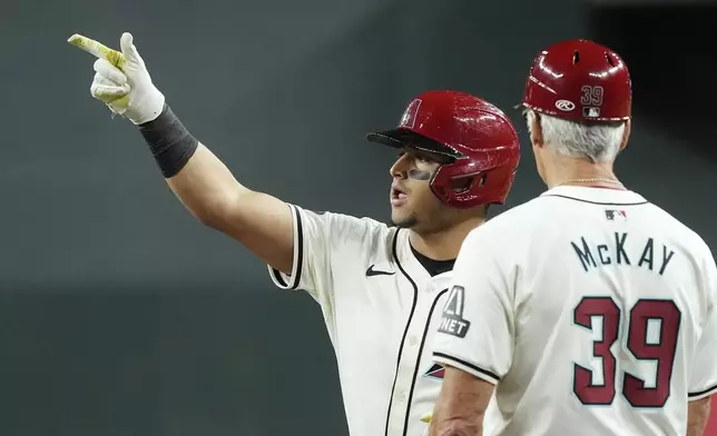 Arizona Diamondbacks' Gabriel Moreno, left, celebrates his run-scoring single against the San Francisco Giants as Diamondbacks first base coach Dave McKay (39) looks on during the second inning of a baseball game Wednesday, Sept. 25, 2024, in Phoenix. (AP Photo/Ross D. Franklin)