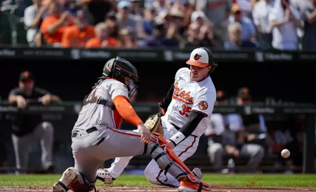 Baltimore Orioles' Adley Rutschman (35) slides into home plate to score in front of San Francisco Giants catcher Patrick Bailey (14) on a hit by Jackson Holliday during the fourth inning of a baseball game, Thursday, Sept. 19, 2024, in Baltimore. (AP Photo/Stephanie Scarbrough)