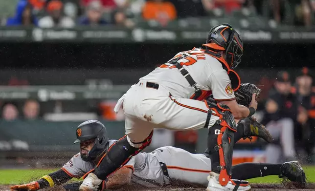 San Francisco Giants' Heliot Ramos slides into home base to score in front of Baltimore Orioles catcher James McCann during the fourth inning of a baseball game, Wednesday, Sept. 18, 2024, in Baltimore. (AP Photo/Stephanie Scarbrough)