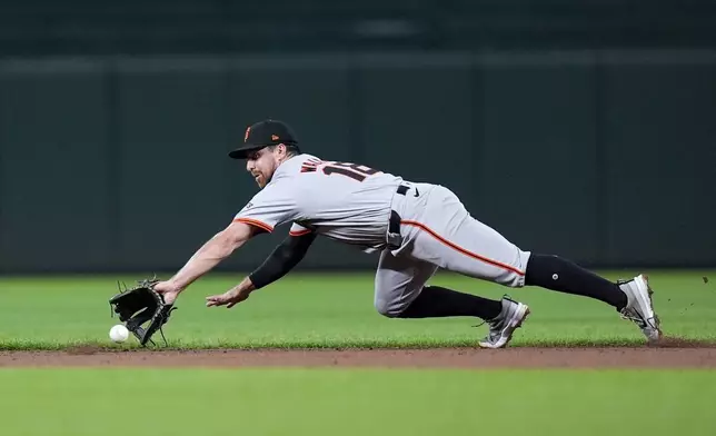 San Francisco Giants second baseman Donovan Walton (18) dives to field a ball hit by Baltimore Orioles' Anthony Santander to make the throw to first baseman LaMonte Wade Jr. for the out during the second inning of a baseball game, Tuesday, Sept. 17, 2024, in Baltimore. (AP Photo/Stephanie Scarbrough)