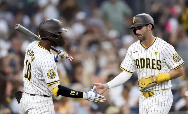 San Diego Padres' Tyler Wade, right, is greeted by Jurickson Profar, left, after scoring off a single hit by designated hitter Luis Arraez during the fifth inning of a baseball game against the San Francisco Giants, Saturday, Sept. 7, 2024, in San Diego. (AP Photo/Ryan Sun)