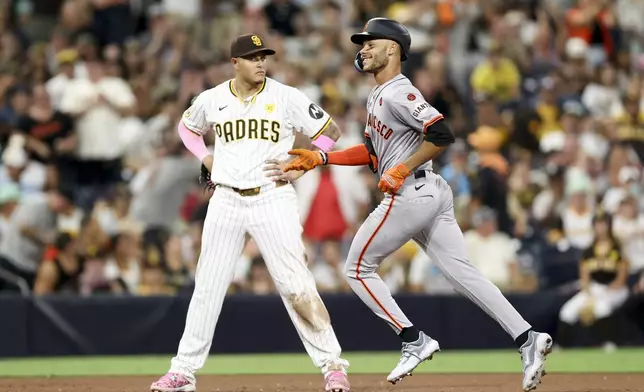 San Francisco Giants' Grant McCray, right, celebrates next to San Diego Padres third baseman Manny Machado, left, after hitting a two-run home run during the ninth inning of a baseball game Saturday, Sept. 7, 2024, in San Diego. (AP Photo/Ryan Sun)