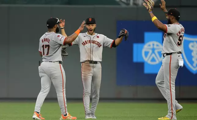 San Francisco Giants' Heliot Ramos (17), Grant McCray, center, and Jerar Encarnacion, right, celebrate after their baseball game against the Kansas City Royals Saturday, Sept. 21, 2024, in Kansas City, Mo. The Giants won 9-0. (AP Photo/Charlie Riedel)