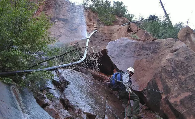 FILE - In this undated photo provided by the National Park Service shows a water spraying from a break in an exposed section of the Grand Canyon trans-canyon waterline as a worker attempts repairs. (National Park Service via AP, File)