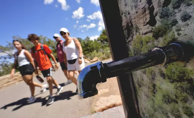 A group of day visitors walk past a closed water bottle tap along the Rim Trail, as visitors won't be able to stay overnight in hotels or refill water bottles at Grand Canyon National Park after a series of breaks in the only pipeline that serves the popular tourist destination, Thursday, Aug. 29, 2024, in Grand Canyon, Ariz. (AP Photo/Matt York)