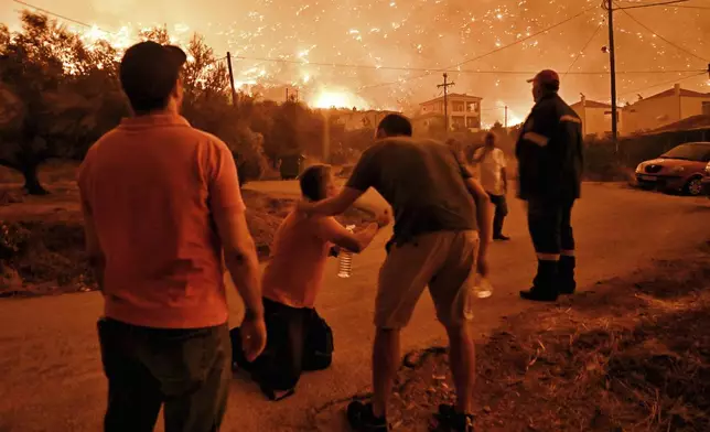 A resident reacts as a wildfire approaches the village of Ano Loutro as fanned by strong winds raged uncontrolled despite the attempts of hundreds of firefighters to stop it, some 131 kilometers (81 miles) west of Athens, Greece, in the region of Corinthia, late Sunday, Sept. 29, 2024. (AP Photo)