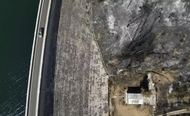 A car passes the dam of Marathon Lake, over a blackened forest which had been burned in a mid-August wildfire, about 36 kilometres (22 miles) north of Athens, Thursday, Aug. 22, 2024. (AP Photo/Thanassis Stavrakis)