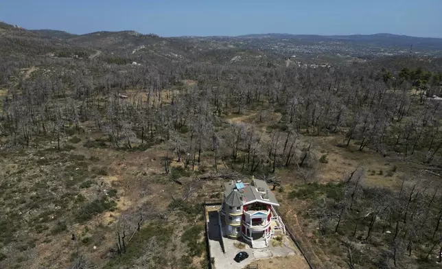 A house is seen in front of a forest which had been burned in an Aug. 2021 wildfire, in Ippokratios Politia village, about 35 kilometres (21 miles) north of Athens, Friday, Aug. 23, 2024. (AP Photo/Thanassis Stavrakis)