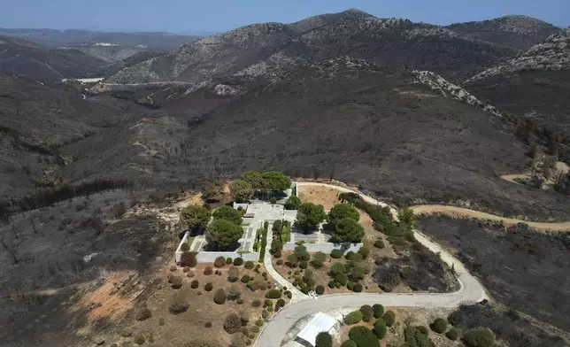 Blackened mountains are seen around the German Military Cemetery, which had been burned in a mid-August wildfire, at Dionysos northern suburb of Athens, Thursday, Aug. 22, 2024. (AP Photo/Thanassis Stavrakis)