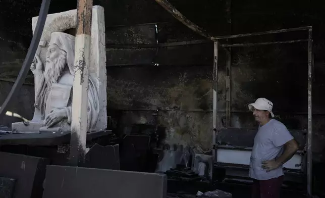 Sculptor Vangelis Ilias stands in the blackened remains of his workshop, which had been burned in a mid-August wildfire, in Halandri suburb in northern Athens, Thursday, Aug. 22, 2024. (AP Photo/Thanassis Stavrakis)