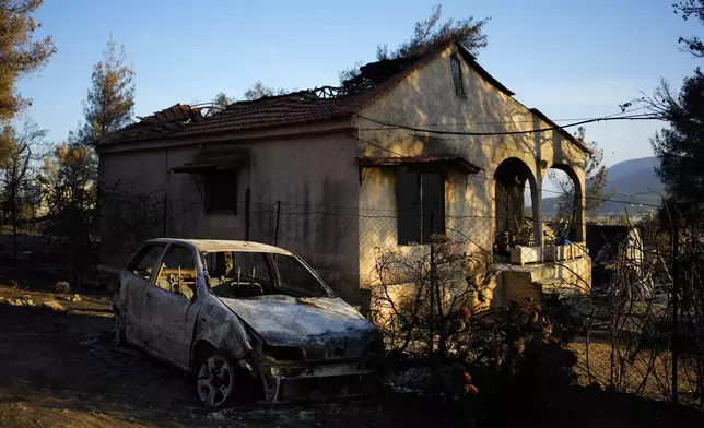 Damaged house and car, which had been burned in a mid-August wildfire, are seen in Halandri suburb in northern Athens, Sunday, Aug. 25, 2024. (AP Photo/Thanassis Stavrakis)