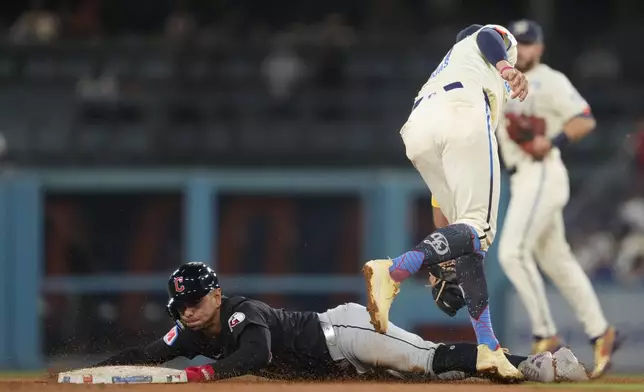 Cleveland Guardians' Andrés Giménez, left, steals second base ahead of a throw to Los Angeles Dodgers shortstop Miguel Rojas during the seventh inning of a baseball game in Los Angeles, Saturday, Sept. 7, 2024. (AP Photo/Ashley Landis)