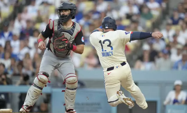 Los Angeles Dodgers' Max Muncy (13) scores off of a sacrifice fly hit by Gavin Lux during the first inning of a baseball game against the Cleveland Guardians in Los Angeles, Saturday, Sept. 7, 2024. (AP Photo/Ashley Landis)