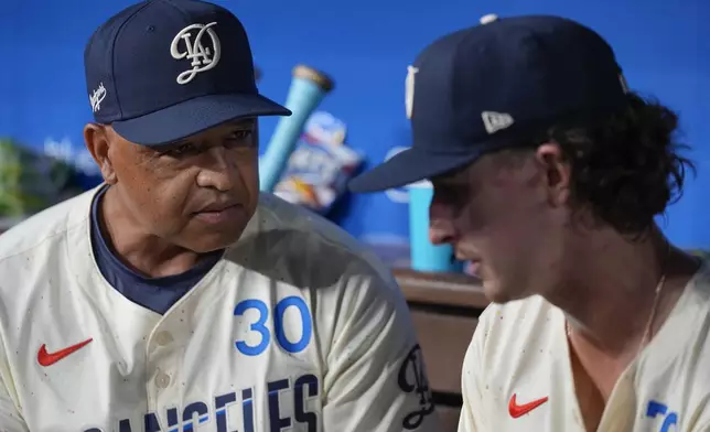 Los Angeles Dodgers manager Dave Roberts (30) talks with relief pitcher Justin Wrobleski in the dugout during the fourth inning of a baseball game against the Cleveland Guardians in Los Angeles, Saturday, Sept. 7, 2024. (AP Photo/Ashley Landis)