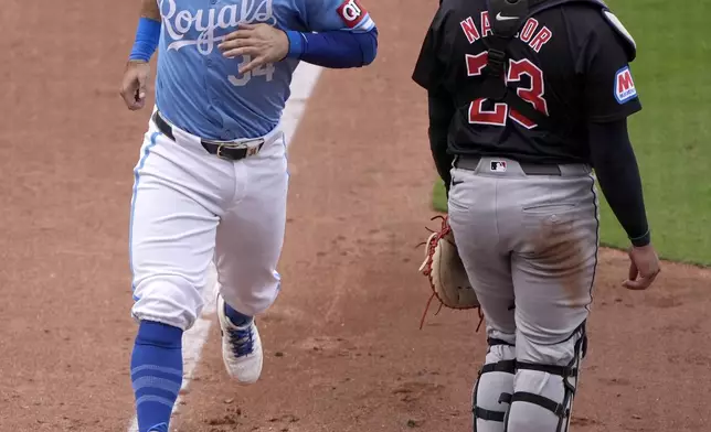 Kansas City Royals' Freddy Fermin (34) runs home past Cleveland Guardians catcher Bo Naylor (23) on a sacrifice fly by Kyle Isbel during the eighth inning of a baseball game Monday, Sept. 2, 2024, in Kansas City, Mo. (AP Photo/Charlie Riedel)