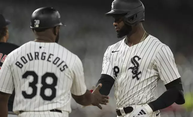 Chicago White Sox's Luis Robert Jr. high fives first base coach Jason Bourgeois after hitting a single during the third inning of a baseball game against the Cleveland Guardians, Tuesday, Sept. 10, 2024, in Chicago. (AP Photo/Melissa Tamez)