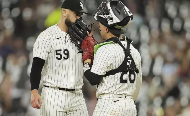 Chicago White Sox's Sean Burke, left, chats with catcher Korey Lee on the mound during the seventh inning of a baseball game against the Cleveland Guardians, Tuesday, Sept. 10, 2024, in Chicago. (AP Photo/Melissa Tamez)