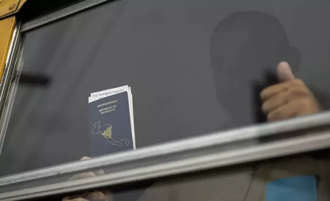 A Nicaraguan citizen shows his passport from a bus after being released from a Nicaraguan jail and landing at the airport in Guatemala City, Thursday, Sept. 5, 2024. (AP Photo/Moises Castillo)