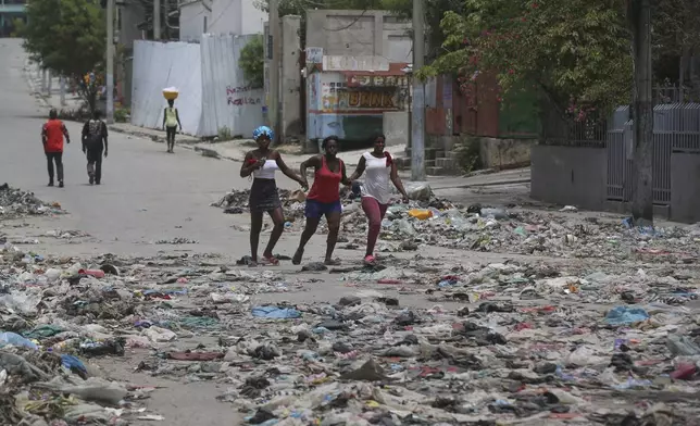 People walk down a street covered with trash in downtown Port-au-Prince, Haiti, Thursday, Sept. 5, 2024. (AP Photo/Odelyn Joseph)