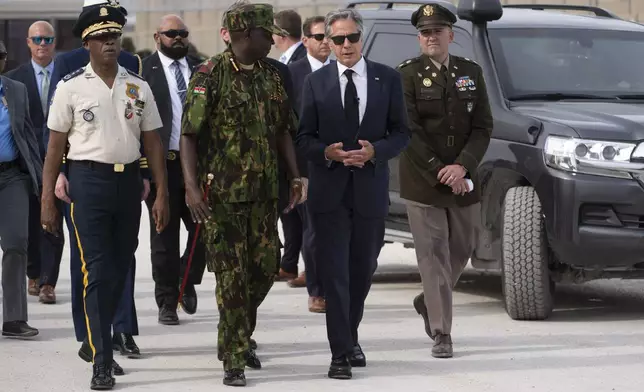 U.S. Secretary of State Antony Blinken, in sunglasses, and Commander of the Multinational Security Support Mission Commander Godfrey Otunge chat at the MSS base in Port-au-Prince, Haiti, Thursday, Sept. 5, 2024. (Roberto Schmidt/Pool photo via AP)