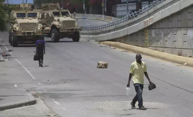 A man walks near armored vehicles of Kenyan police officers part of a UN-backed multinational in Port-au-Prince, Haiti, Wednesday, Sept. 4, 2024. (AP Photo/Odelyn Joseph)