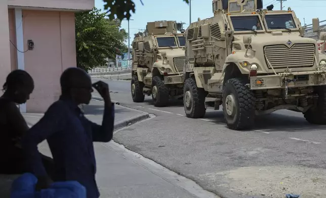 Kenyan police officers, part of a UN-backed multinational force, drive past residents in armored vehicles on the streets of Port-au-Prince, Haiti, Wednesday, Sept. 4, 2024. (AP Photo/Odelyn Joseph)