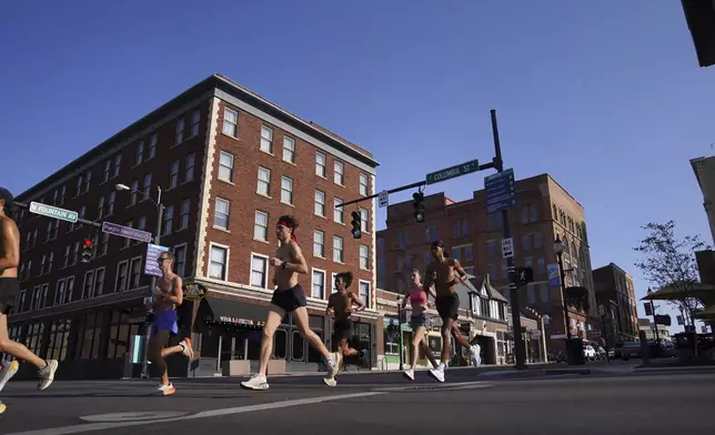 Runners pass through Downtown Springfield, Ohio, Monday, Sept. 16, 2024. (AP Photo/Jessie Wardarski)