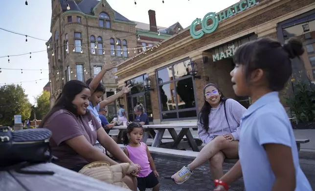 Alondra Nunez, left, and her sister Monserrat, second from right, sit with family members outside of The Market, where their brother owns the restaurant Chido's Tacos, Monday, Sept. 16, 2024, in Springfield, Ohio. (AP Photo/Jessie Wardarski)