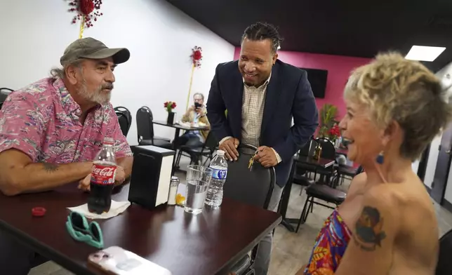 Karl Mattila, left, and his wife Linda, of Medway, Ohio, talk with Haitian and longtime Springfield resident Jacob Payen at Rose Goute Creole Restaurant in Springfield, Ohio, Monday, Sept. 16, 2024. (AP Photo/Jessie Wardarski)