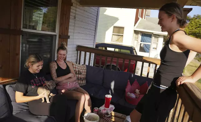 Lifelong Springfield residents Lainey Bogard, left, Kelsey Fannon, center, and Kassidy Fannon sit on the front porch with their dog, Monday, Sept. 16, 2024, in Springfield, Ohio. (AP Photo/Jessie Wardarski)