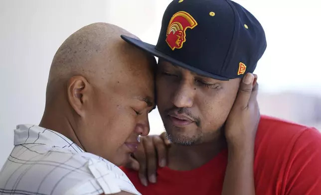 FILE - JP Mayoga, right, a chef at the Westin Maui, Kaanapali, and his wife, Makalea Ahhee, hug on their balcony at the hotel and resort, Sunday, Aug. 13, 2023, near Lahaina, Hawaii. About 200 employees were living there with their families. (AP Photo/Rick Bowmer, File)