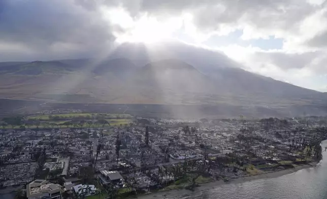 FILE - Rays of sunlight pierce through the clouds, Thursday, Aug. 10, 2023, above homes burned by wildfires in Lahaina, Hawaii. (AP Photo/Rick Bowmer, File)