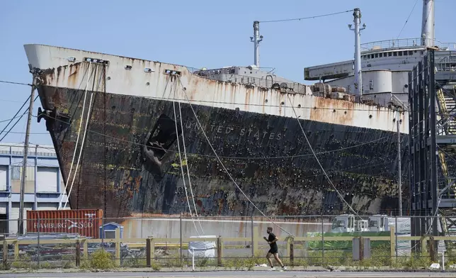 A person runs past the S.S. United States moored on the Delaware River in Philadelphia, Wednesday, Sept. 4, 2024. (AP Photo/Matt Rourke)