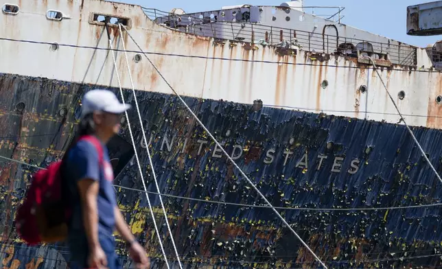 A person walks past the S.S. United States moored on the Delaware River in Philadelphia, Wednesday, Sept. 4, 2024. (AP Photo/Matt Rourke)