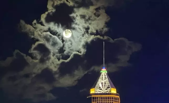 The full moon is shrouded in cloud above a Hong Kong skyscraper on the night of the Mid-Autumn Festival, which is a big traditional holiday around Asia, Tuesday, Sept. 17, 2024. (AP Photo)