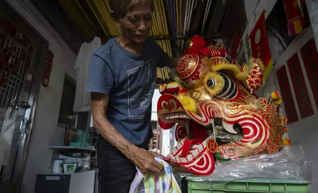 Villager Lo Yuet-ping cleans the head prop that's used in the traditional "Qilin" Dance at the Cha Kwo Ling village in east Kowloon, Hong Kong, Sunday, Aug. 25, 2024. (AP Photo/Chan Long Hei)