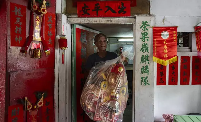 Villager Lo Yuet-ping carries the head prop that's used in the traditional "Qilin" Dance at the Cha Kwo Ling village in east Kowloon, Hong Kong, Sunday, Aug. 25, 2024. (AP Photo/Chan Long Hei)