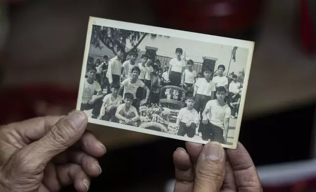 Villager Lo Yuet-ping holds up an old black and white photo where he can be seen in the second from top right at the Cha Kwo Ling village in east Kowloon, Hong Kong, Sunday, Aug. 25, 2024. (AP Photo/Chan Long Hei)