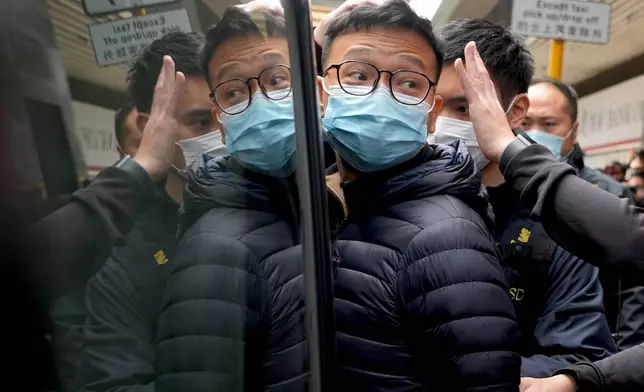 FILE - Then Editor of Stand News Patrick Lam, center, is escorted by police officers into a van after they searched evidence at his office in Hong Kong, Dec. 29, 2021. (AP Photo/Vincent Yu, File)