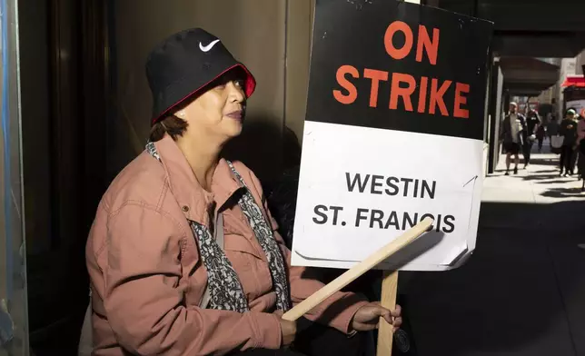 Edralina Lapid holds a sign as hotel workers picket outside the Westin St. Francis Monday, Sept. 2, 2024, in San Francisco. (AP Photo/Benjamin Fanjoy)