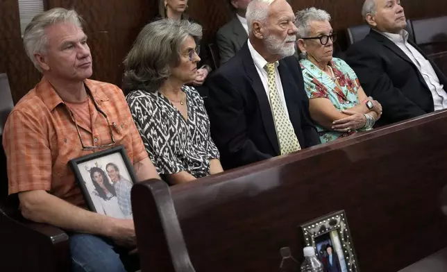 Family members of Dennis Tuttle and Rhogena Nicholas bring a photograph of the couple to the trial of retired Houston Police Department officer Gerald Goines Monday, Sept. 9, 2024 at Harris County Criminal Courthouse in Houston. Goines' trial on two felony murder charges in the January 2019 deaths of Tuttle and Nicholas began Monday. (Yi-Chin Lee/Houston Chronicle via AP)