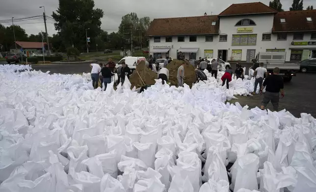 People fill sandbags to reinforce the dam due to the flooding of the Danube river at Tahitotfalu, Hungary, on Monday, Sept. 16, 2024. (AP Photo/Denes Erdos)