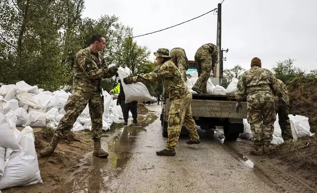 Soldiers build barriers with sandbags against flood water at the bank of Danube River in Pilismarot, Hungary, Monday, Sept. 16, 2024. (Robert Hegedus/MTI via AP)