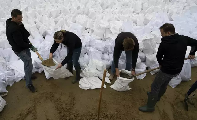 People fill sandbags to reinforce the dam due to the flooding of the Danube river at Tahitotfalu, Hungary, on Monday, Sept. 16, 2024. (AP Photo/Denes Erdos)