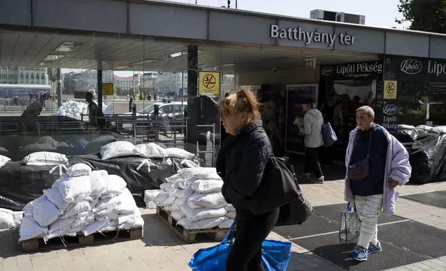 People walk next to a metro station surrounded by sandbags as the Danube river floods it's banks, central Budapest, Thursday, Sept. 19, 2024. (AP Photo/Denes Erdos)