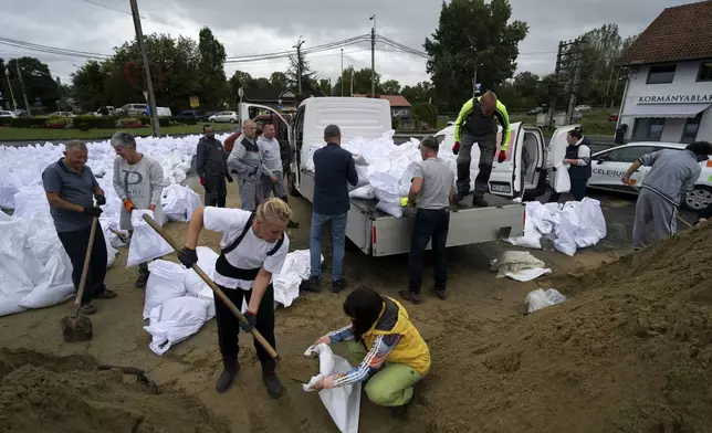 People fill sandbags to reinforce the dam due to the flooding of the Danube river at Tahitotfalu, Hungary, on Monday, Sept. 16, 2024. (AP Photo/Denes Erdos)