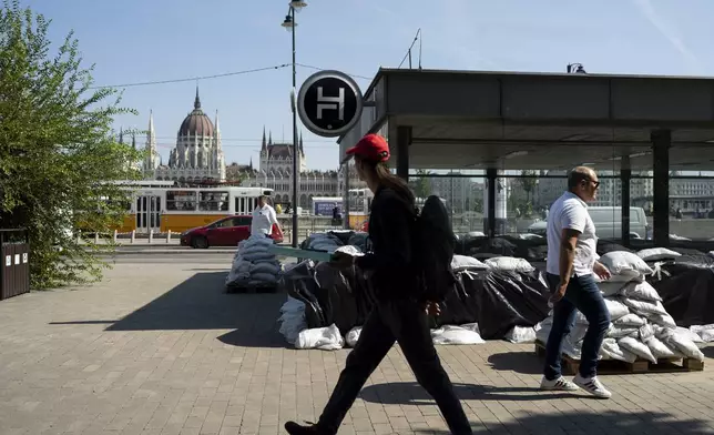 People walk by a metro station protected by sandbags as the Danube river floods it's banks, central Budapest, Hungary, Thursday, Sept. 19, 2024. (AP Photo/Denes Erdos)